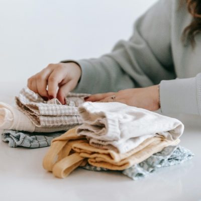 A woman organizing folded clothes on a table at home, emphasizing neatness and lifestyle.