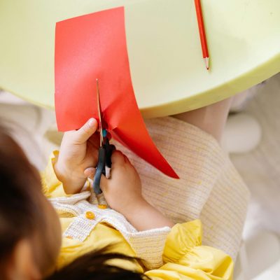 Girl in Yellow Dress Cutting A Red Art Paper