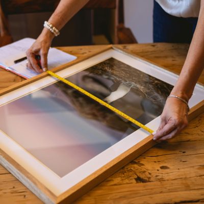 Person Measuring a Picture Frame Using Tape Measure